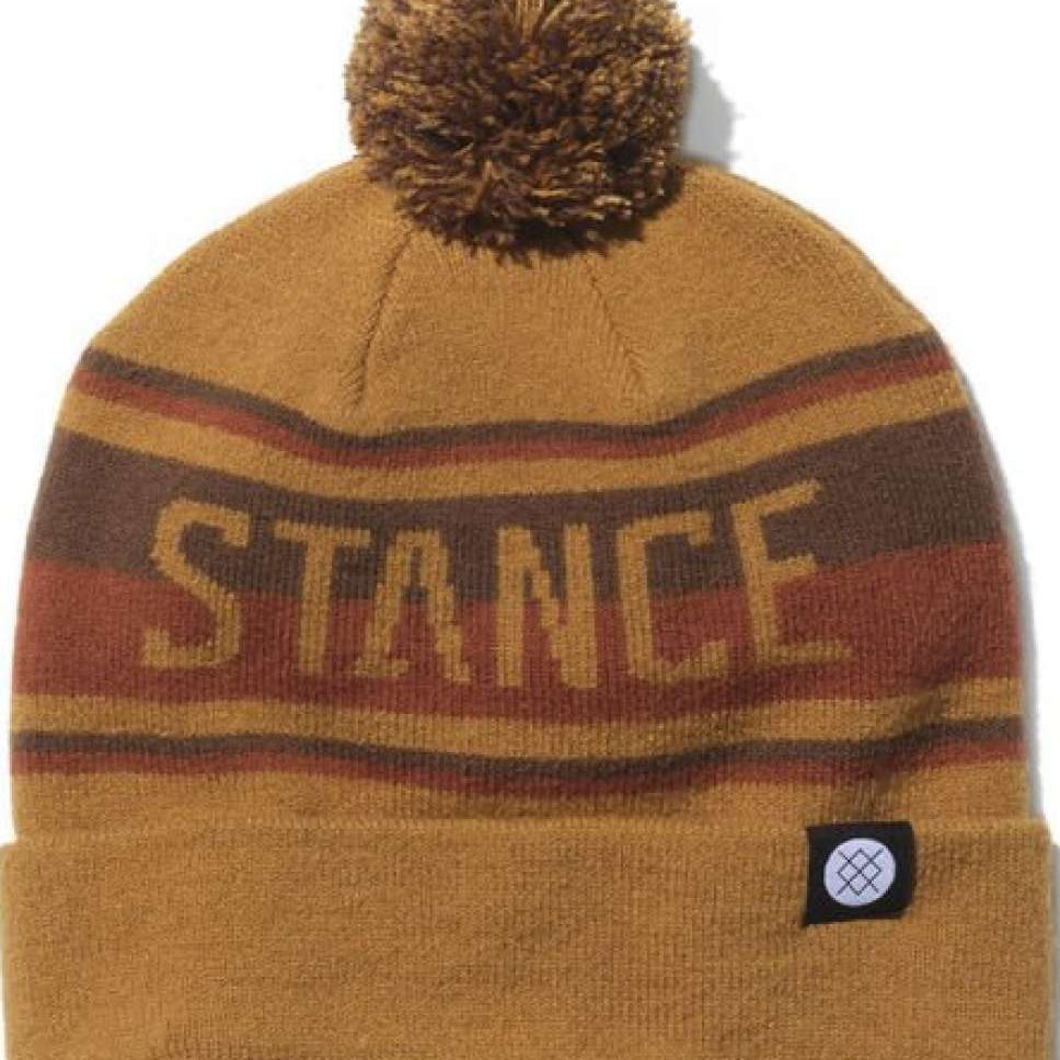Stance OG Pom Beanie 2023 - A tan beanie with a brown pom-pom on top and a repeating pattern of red, yellow, and gray stripes around it.