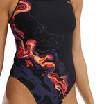 TYR Women's Trinityfit Torch Swimsuit - A black swimsuit with a vibrant, abstract design featuring shades of orange and pink.