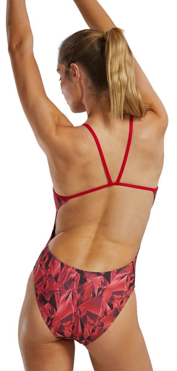 TYR Women's Crystalized Cutout Swimsuit - A red swimsuit with a geometric pattern of darker red and black triangles, worn by a woman from behind, facing left.