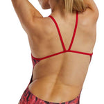 TYR Women's Crystalized Cutout Swimsuit - A red swimsuit with a geometric pattern of darker red and black triangles, worn by a woman from behind, facing left.