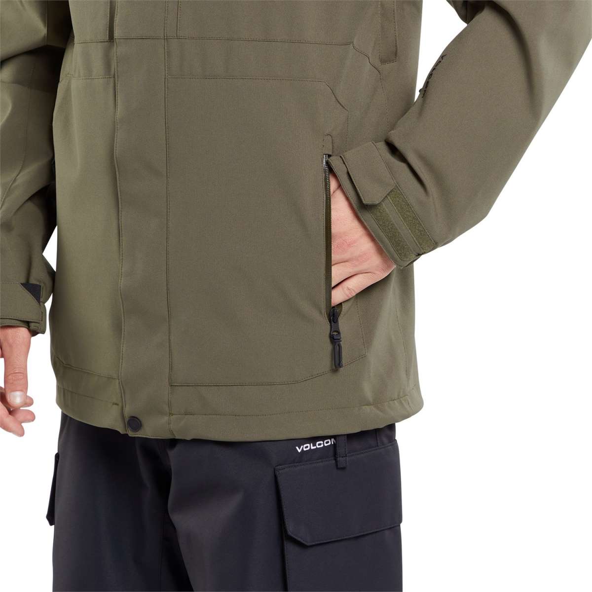 Volcom V.Co Op Shell Jacket 2024 - A dark olive green jacket with a zippered chest pocket and two side pockets, featuring a black zipper pull on the left breast pocket.