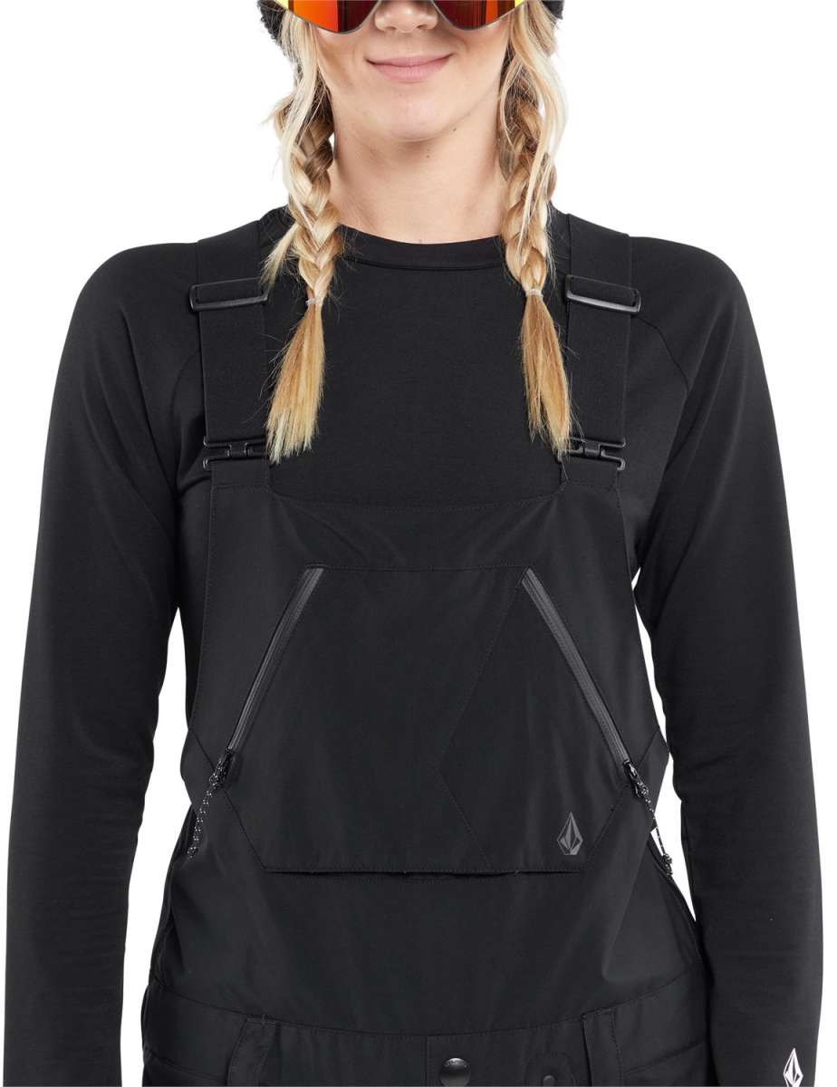 Volcom Women's Elm Stretch GORE-TEX Bib Pant - Black bib pant with diagonal white and grey stripe pattern on left leg, zippered ankle pocket, and adjustable straps.