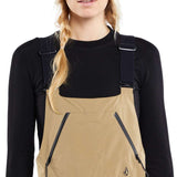 Volcom Women's Elm Stretch GORE-TEX Bib Pant - A pair of tan bib pants with a black zipper on the side and a small logo in the bottom right corner.