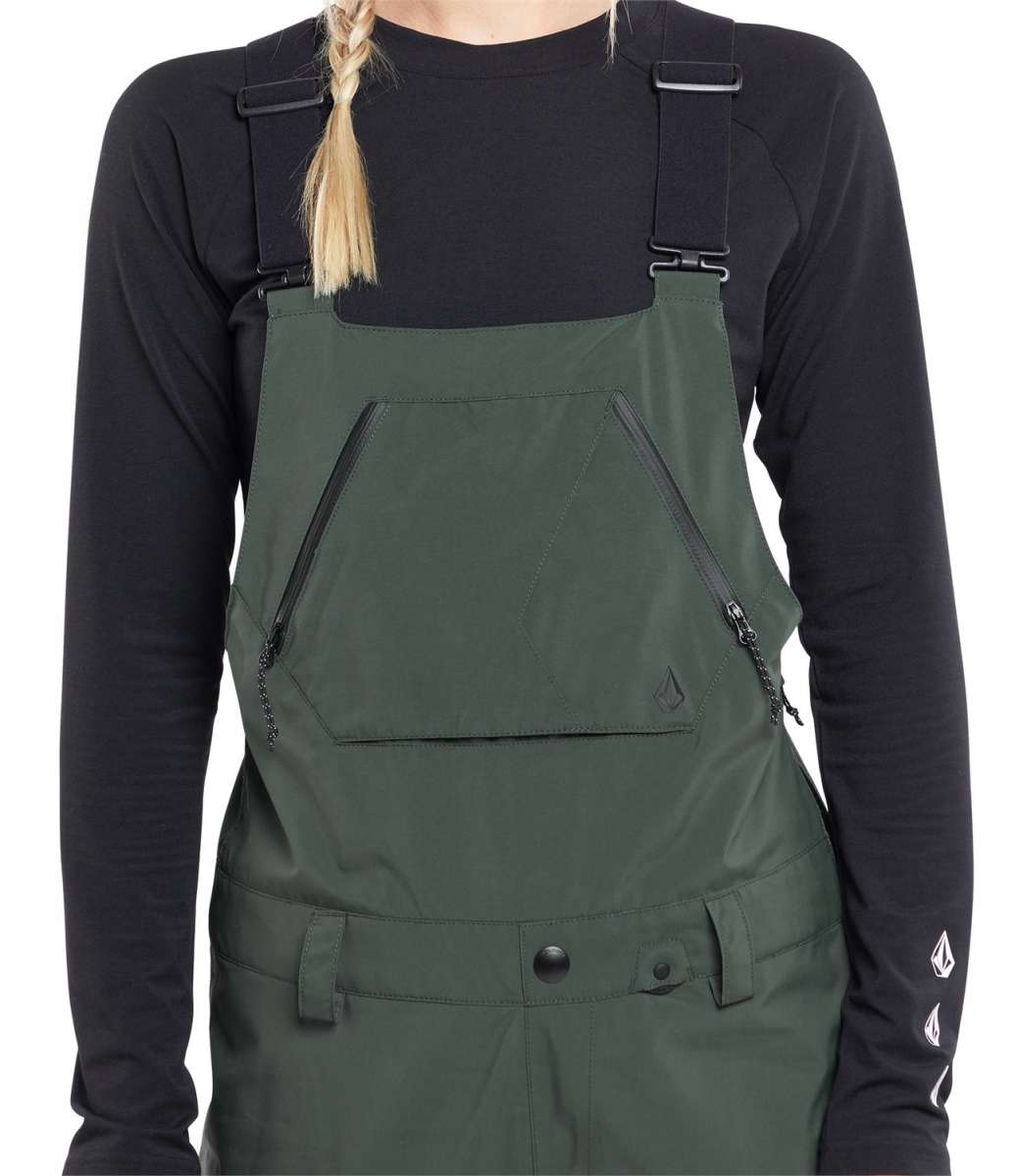Volcom Women's Elm Stretch GORE-TEX Bib Pant - A pair of dark green bib pants with a geometric pattern on the side, featuring adjustable straps and a zippered fly.