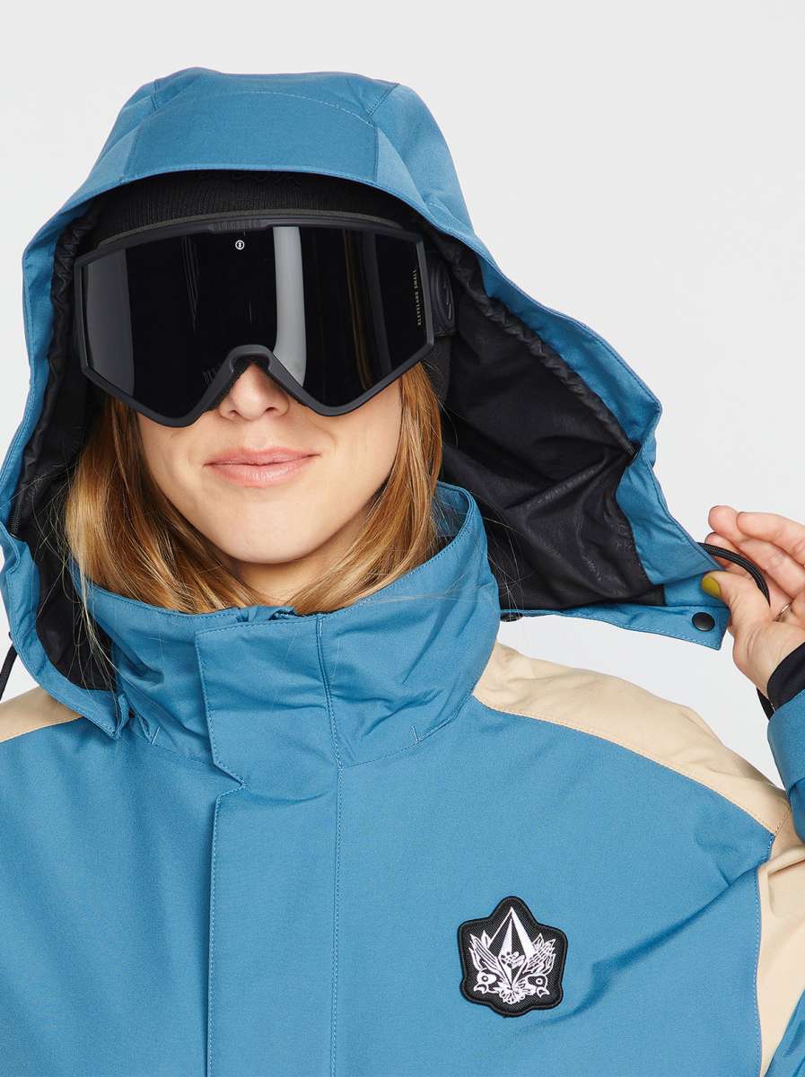 Volcom Women's Melancon GORE-TEX Jacket - A blue and tan jacket with a hood, featuring a black logo patch on the chest.