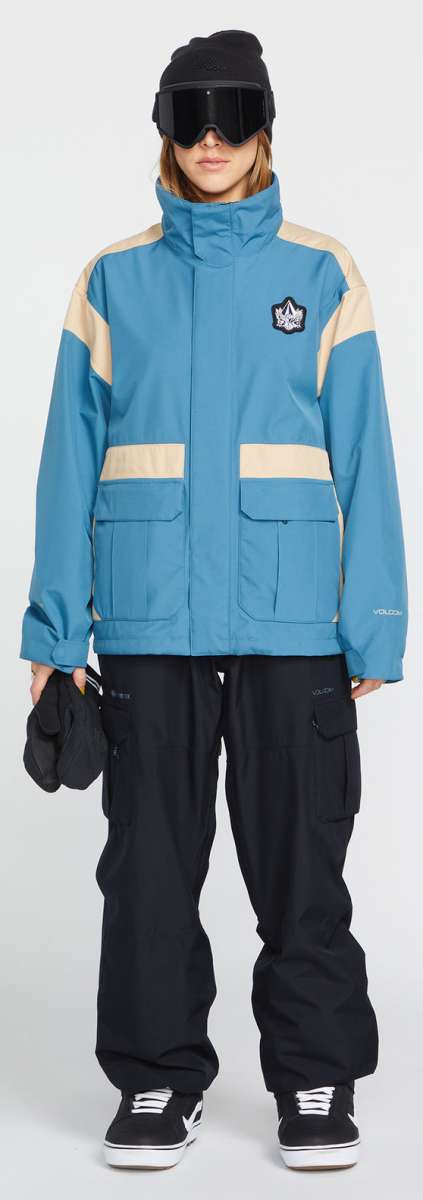 Volcom Women's Melancon GORE-TEX Jacket - A blue jacket with a white stripe on the shoulder and chest, featuring a black logo patch on the left side of the chest.