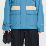 Volcom Women's Melancon GORE-TEX Jacket - A blue jacket with a white stripe on the shoulder and chest, featuring a black logo patch on the left side of the chest.