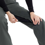 Volcom Women's Species Stretch Pant 2024 - A pair of dark gray pants with a subtle pattern and zippered pockets, worn by a model in an angled pose.