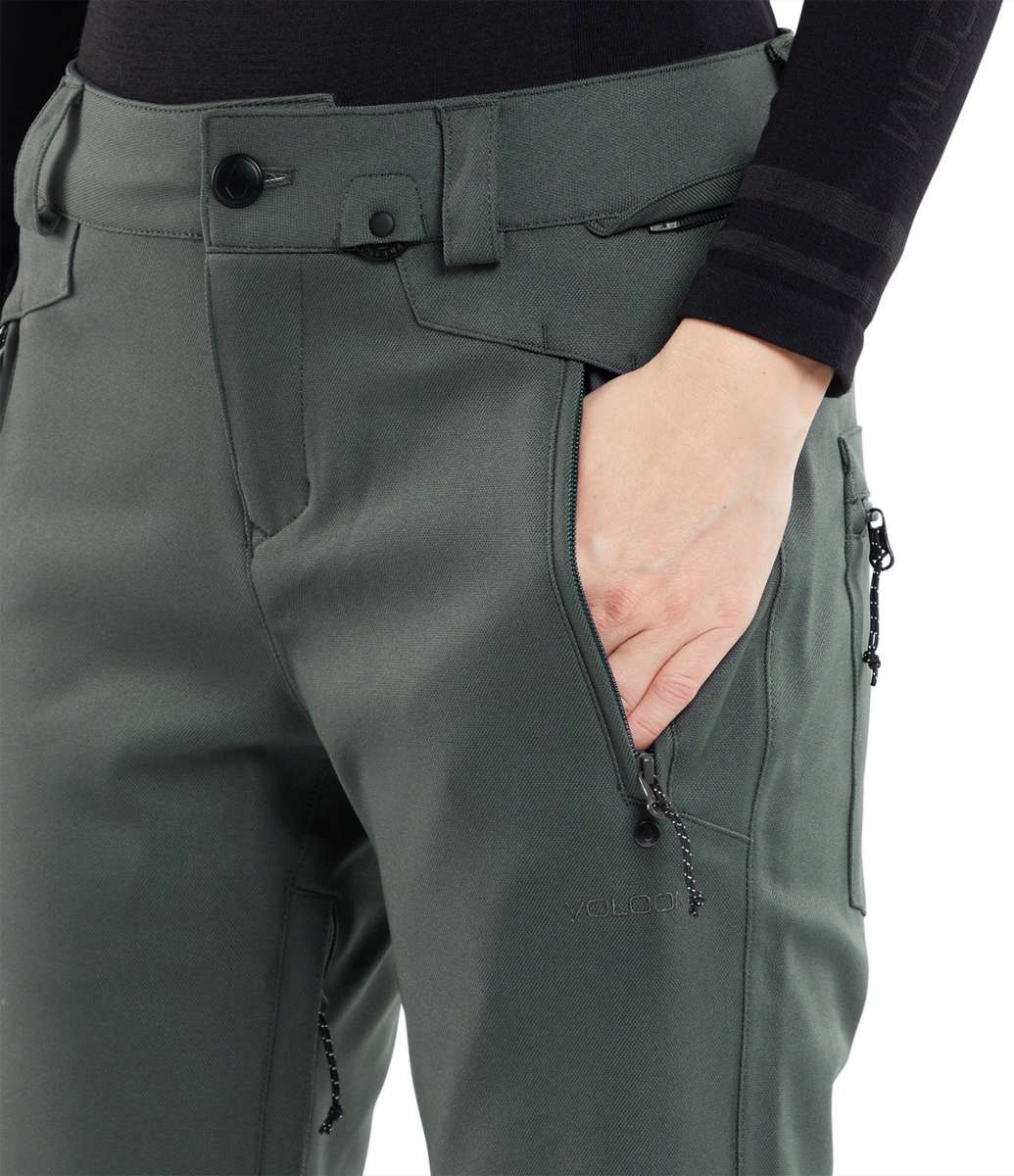 Volcom Women's Species Stretch Pant 2024 - A pair of olive green snow pants with zippered pockets and a black logo on the left thigh.