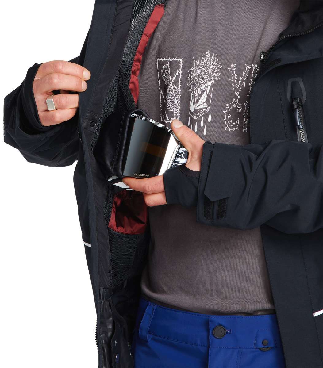 Volcom TDS 2L GORE-TEX Insulated Jacket 2023 - A black jacket with white lettering and a red lining visible inside the open zipper pocket on the left side.