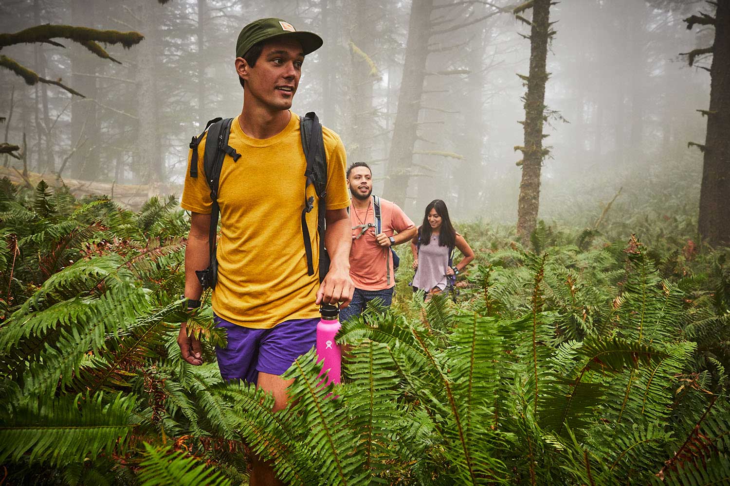 Hydro Flask 32oz Wide Mouth Water Bottle - A pink water bottle with a black lid and white logo, held by a man in a yellow shirt.
