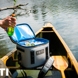Yeti Hopper Flip 8 Personal Cooler - A white cooler with a black handle and zipper, sitting on a wooden dock by the water.
