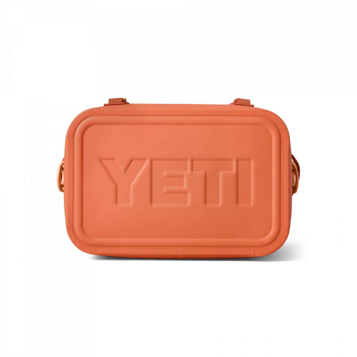 Yeti Hopper Flip 12 Personal Cooler - A coral-colored cooler with a textured pattern on its surface, featuring a handle and two latches on top.