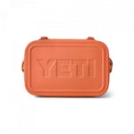 Yeti Hopper Flip 12 Personal Cooler - A coral-colored cooler with a textured pattern on its surface, featuring a handle and two latches on top.