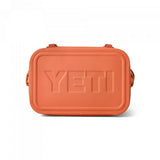 Yeti Hopper Flip 12 Personal Cooler - A coral-colored cooler with a textured pattern on its surface, featuring a handle and two latches on top.
