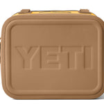 Yeti Hopper Flip 12 Personal Cooler - A tan cooler with a black zipper and handle on top, featuring an embossed "YETI" logo in the center of the lid.
