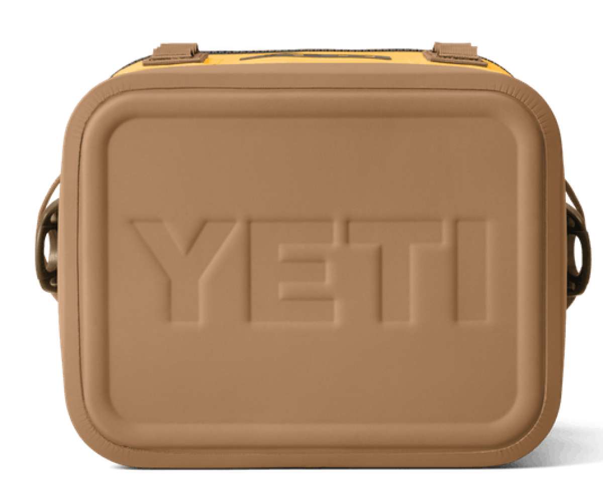 Yeti Hopper Flip 12 Personal Cooler - A tan cooler with a black zipper and handle on top, featuring an embossed "YETI" logo in the center of the lid.