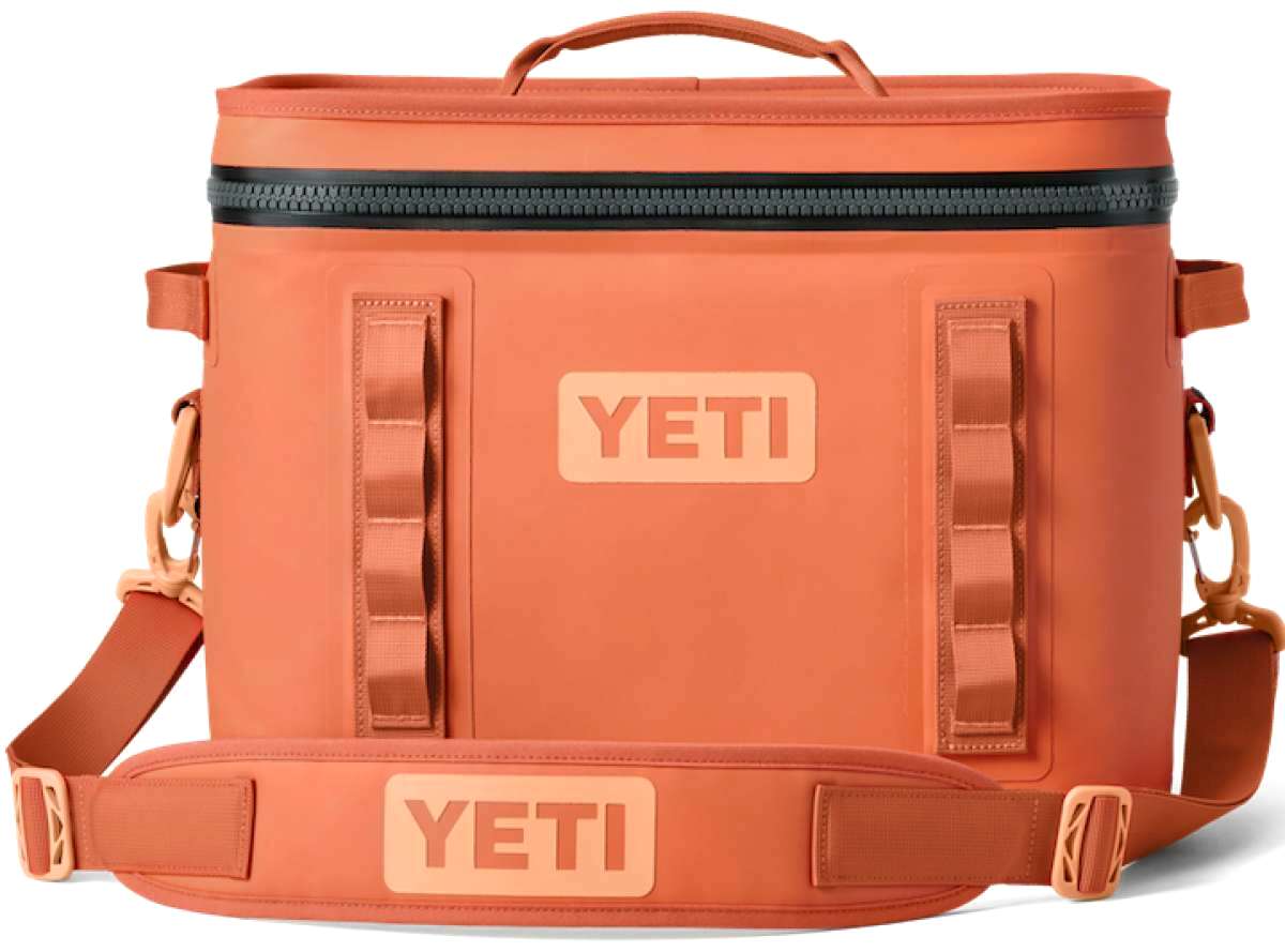 Yeti Hopper Flip 18 Personal Cooler - A coral-colored cooler with a zippered top and two side handles, featuring a textured surface and an embossed logo on one side.