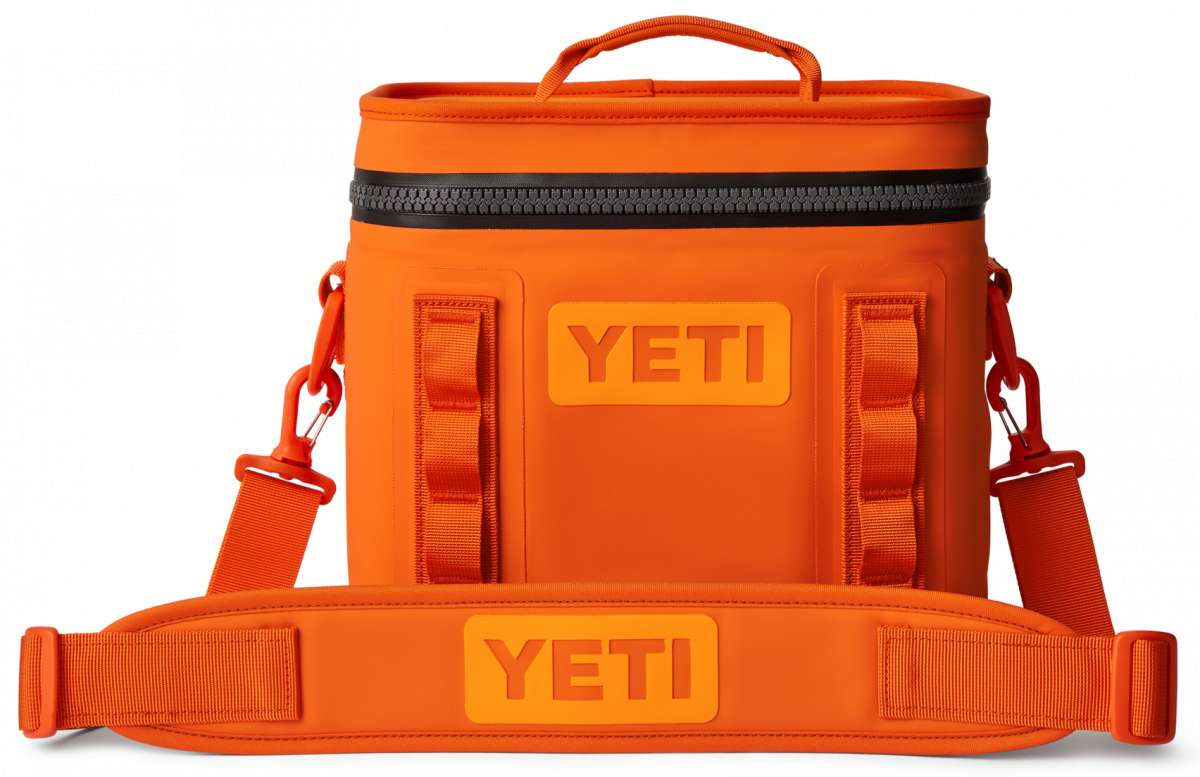 Yeti Hopper Flip 8 Personal Cooler - A small, portable cooler with a handle and wheels for easy transport. It has an orange color and is made of durable material. The brand logo "YETI" is prominently displayed on the front.