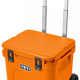 Yeti Roadie 48 Wheeled Cooler - A wheeled cooler with a handle on top and wheels at the bottom, featuring a large logo on the front that says "YETI" in white letters.